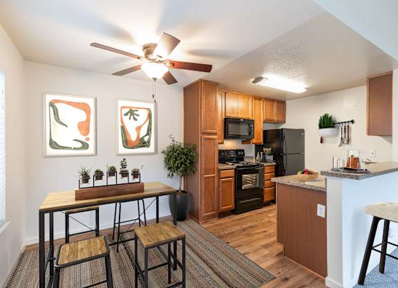 A kitchen with a table and chairs in front of a window at The Woods Apartments, California