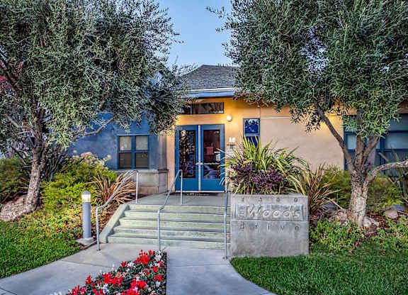 A building with a driveway and a sign that says at The Woods Apartments, California, 95136