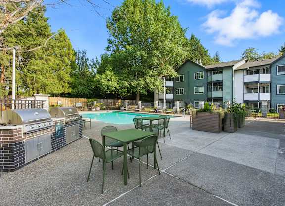 A patio with a table and chairs and a grill.