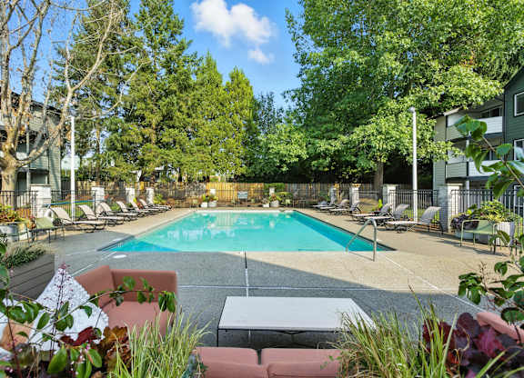 A pool surrounded by trees and chairs.