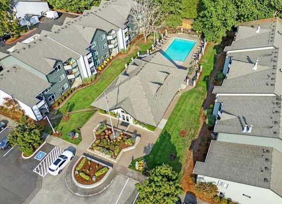 A bird's eye view of a residential area with houses, a pool, and a parking lot.