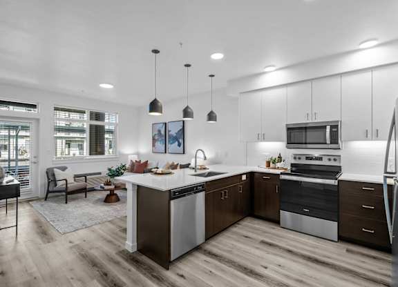an open kitchen and living room with white cabinets and stainless steel appliances