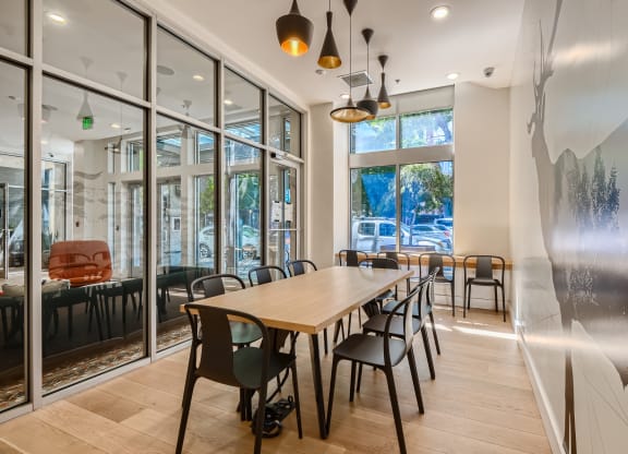 a long table with chairs in a room with large windows
