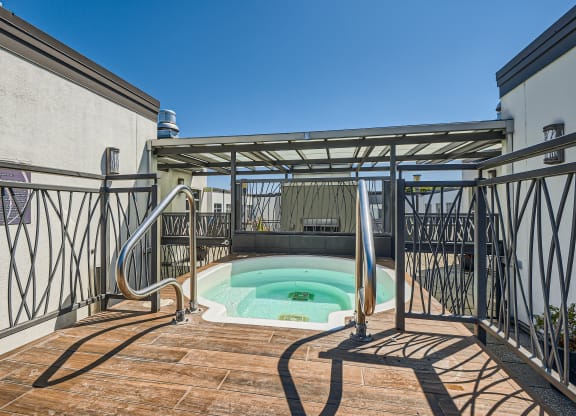 a plunge pool sits on the balcony of a house with metal railing