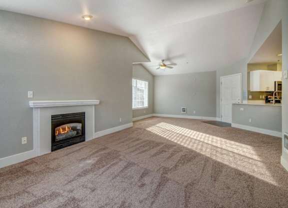 Unfurnished Living Room With Plush Carpet, a Fireplace, and a Sliding Glass Door With Shutters at Clock Tower Village, Washington