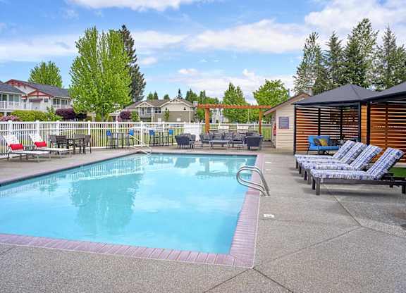 Outdoor Swimming Pool with Lounge Chairs, Shade Gazebos, and Lush Greenery at Clock Tower Village, Washington