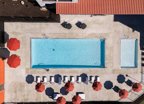 arial view of a swimming pool with umbrellas and tables on a building