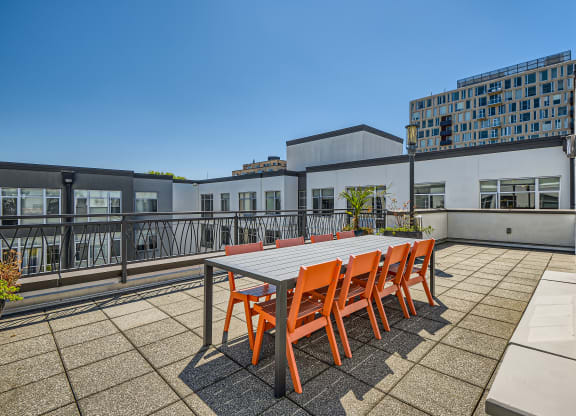 a dining table and chairs on a roof terrace with buildings in the background