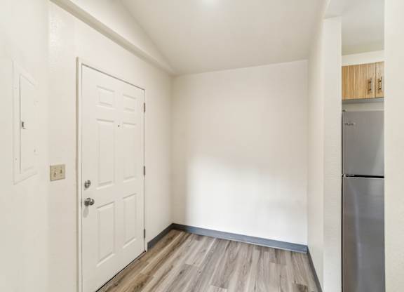 A white door is in a room with a wooden floor.