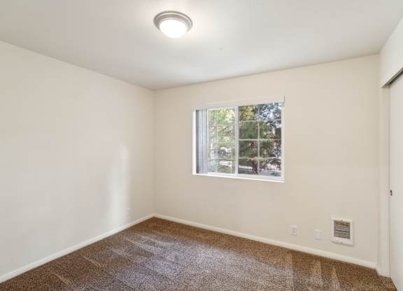 A room with a window and carpeted floor.