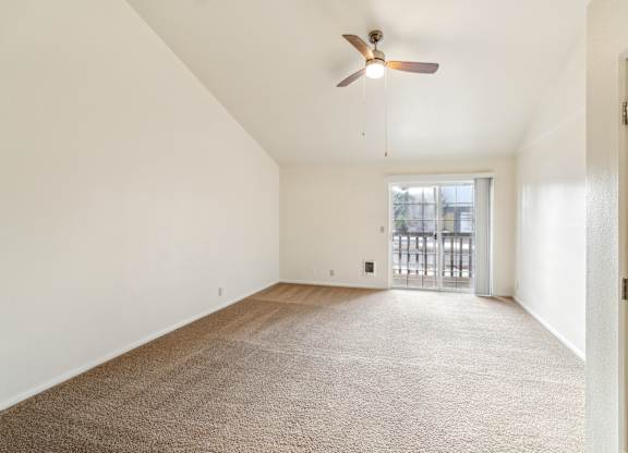 A room with a ceiling fan and carpeted floor.