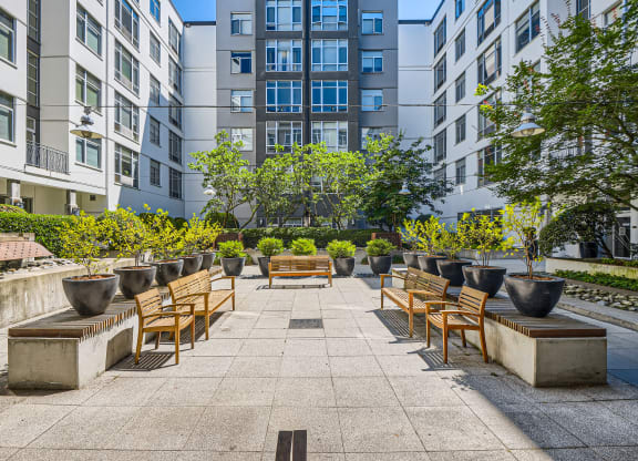 an outdoor patio with benches and potted plants in front of an apartment building