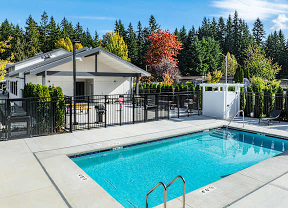 A swimming pool in a backyard with a house and trees in the background.