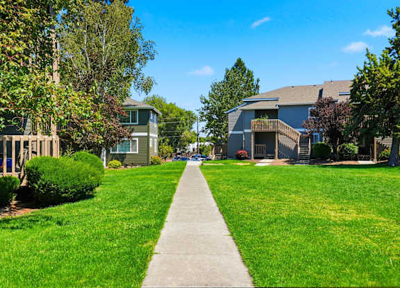 A pathway leads through a grassy area between two buildings.