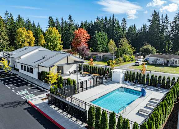 A swimming pool surrounded by trees and a building in the background.