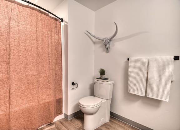 a bathroom with a toilet and a shower curtain and a deer skull on the wall