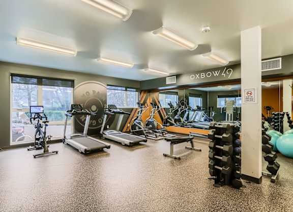 A gym with a variety of equipment including treadmills, exercise bikes, and weight racks.