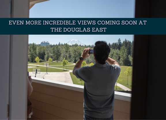 A man is taking a photo of a beautiful landscape from a window.
