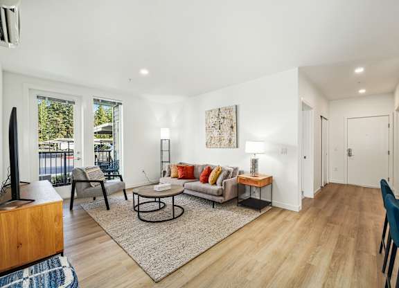 A living room with a couch, chairs, and a rug.