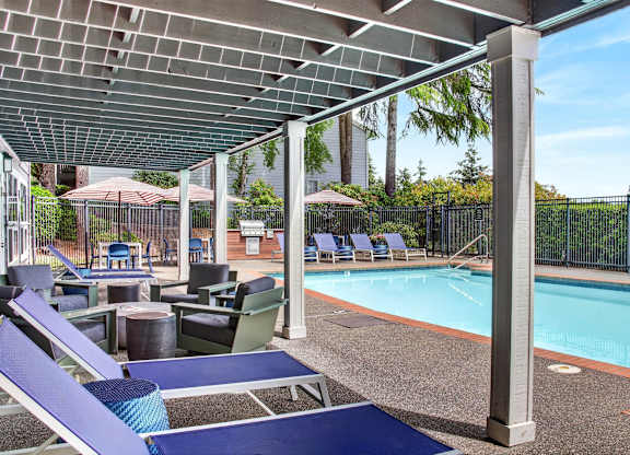 A pool area with a shaded seating area and a pool.