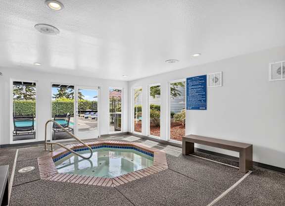 A small indoor pool with a hot tub in the middle of the room.