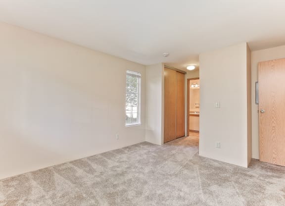 a spacious living room with carpet and a door to a bathroom