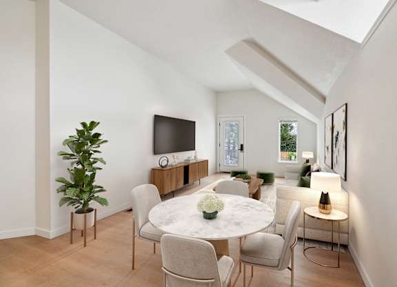 A white dining table with chairs and a television on a wooden cabinet.