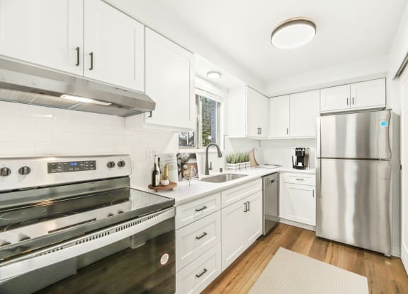 a white kitchen with stainless steel appliances and white cabinets
