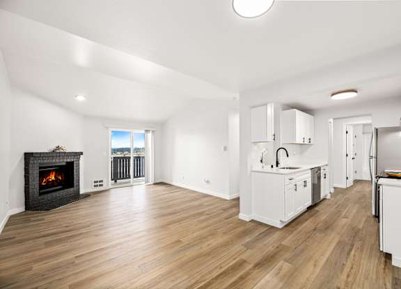 a living room with a fireplace and a kitchen with white cabinets