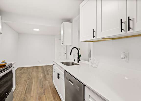 a renovated kitchen with white cabinets and white counter tops and a sink