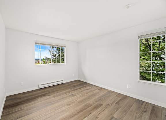 an empty room with white walls and wood floors and a window