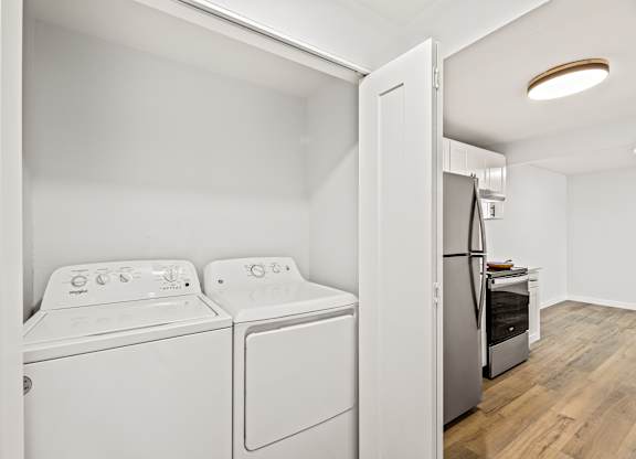 a white washer and dryer in a room with a door to a kitchen