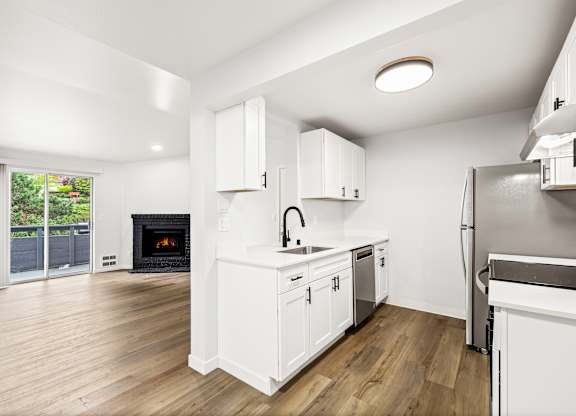 a renovated kitchen with white cabinets and a fireplace