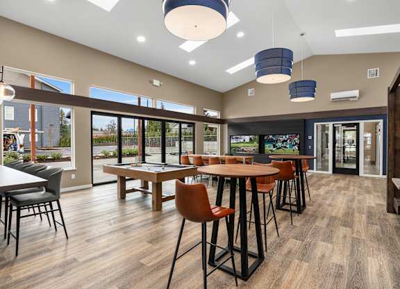 A room with a long table surrounded by chairs and a bar area.