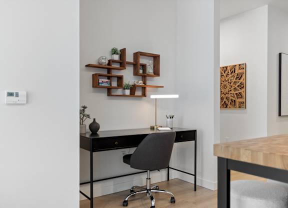 A modern home office with a black desk and a black chair.