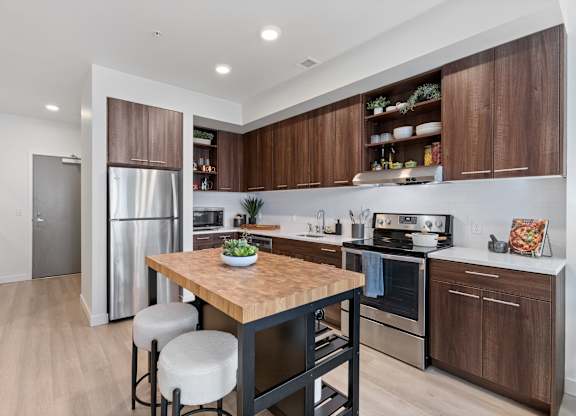 A modern kitchen with a wooden table and stools.