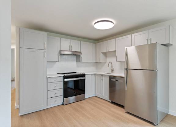 A kitchen with a refrigerator, oven, and sink.