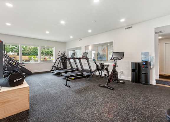 A spacious gym with a variety of equipment including treadmills, stationary bikes, and weight machines.