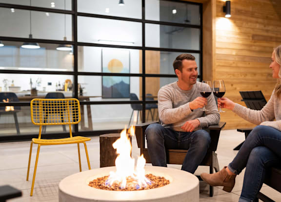 A man and a woman are sitting by a fire in a modern room.