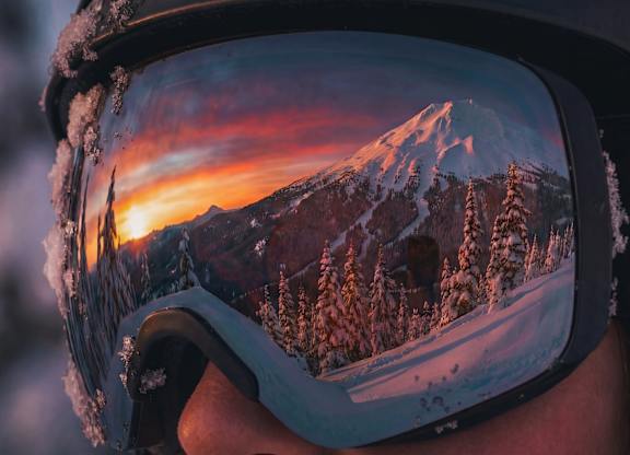 A person is wearing a pair of goggles that reflect a beautiful mountain landscape.