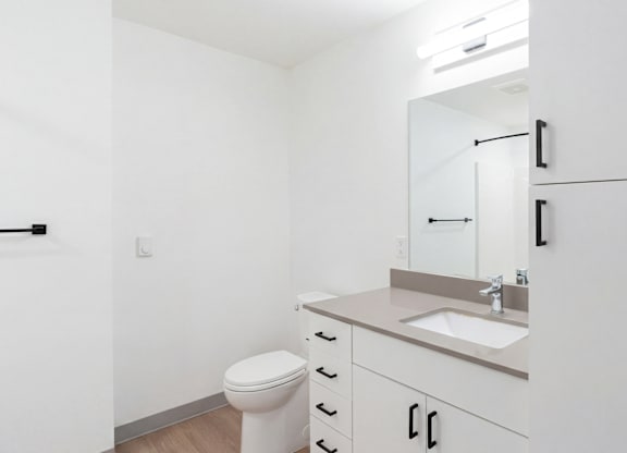 A white bathroom with a toilet, sink, and mirror.