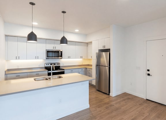 A modern kitchen with a stainless steel refrigerator and a white countertop.