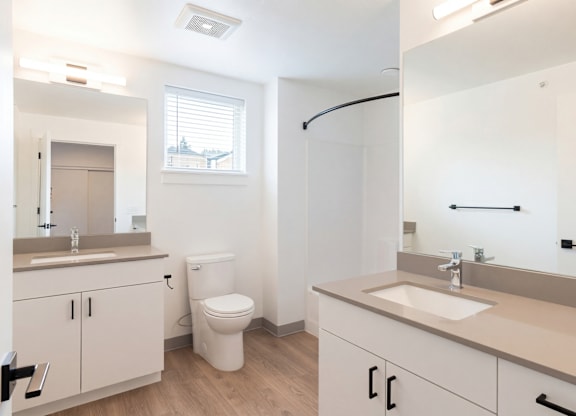 A white bathroom with a toilet, sink, and mirror.