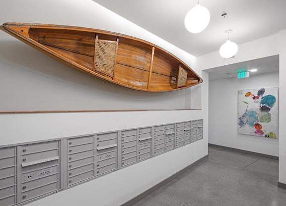 A wooden boat mounted on a wall above a row of mailboxes.
