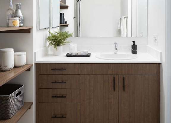 A bathroom with a white sink and brown cabinets.