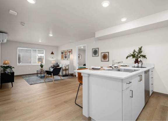 A modern kitchen with white cabinets and a wooden floor.