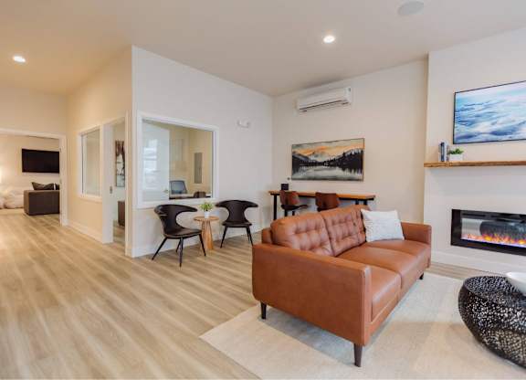 A living room with a brown leather couch and a fireplace.