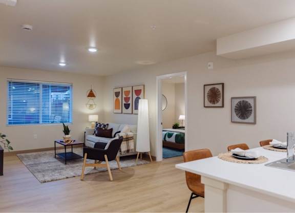 A modern kitchen with a white countertop and a dining area with a table and chairs.