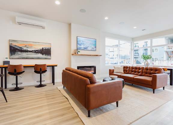 A living room with a brown leather couch and a painting on the wall.