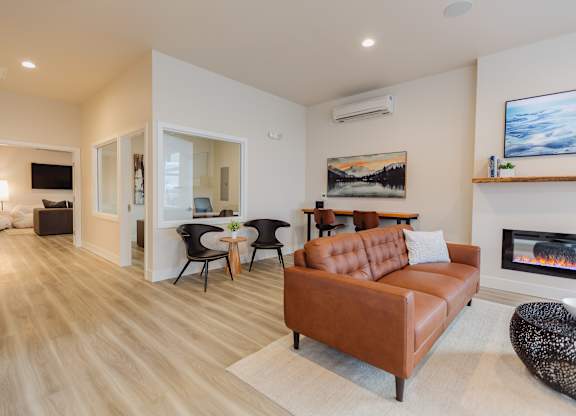 A living room with a brown leather couch and a fireplace.